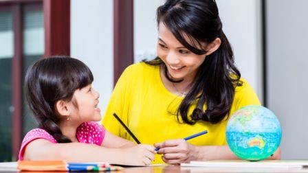 Mom having fun helping her daughter with her homework,