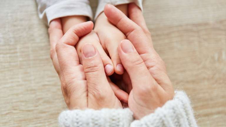 Mom holding hand of her child.